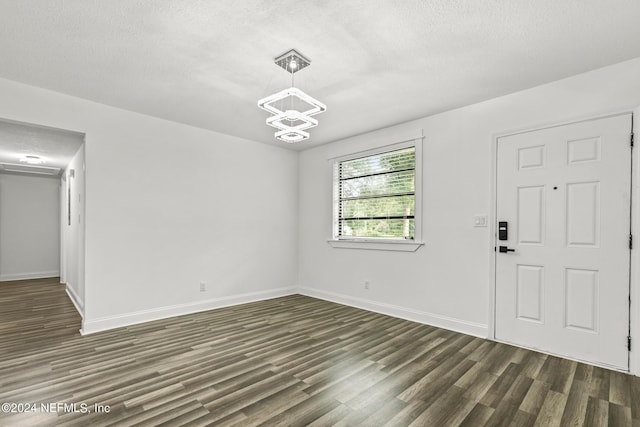 interior space with dark wood-type flooring, an inviting chandelier, and a textured ceiling