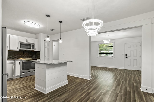 kitchen with pendant lighting, appliances with stainless steel finishes, tasteful backsplash, white cabinets, and a kitchen island