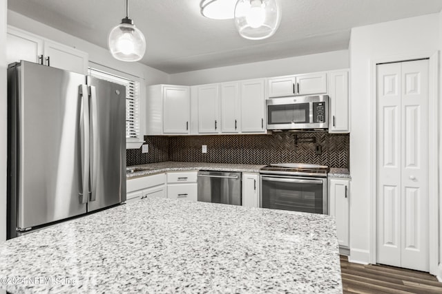 kitchen featuring stainless steel appliances, white cabinetry, decorative backsplash, and decorative light fixtures