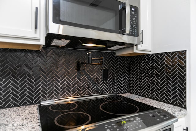 kitchen featuring white cabinetry, appliances with stainless steel finishes, light stone countertops, and backsplash