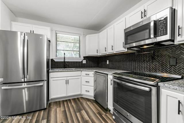 kitchen featuring sink, appliances with stainless steel finishes, light stone countertops, white cabinets, and decorative backsplash