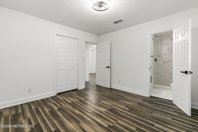 unfurnished bedroom featuring ensuite bath, dark hardwood / wood-style floors, and a closet