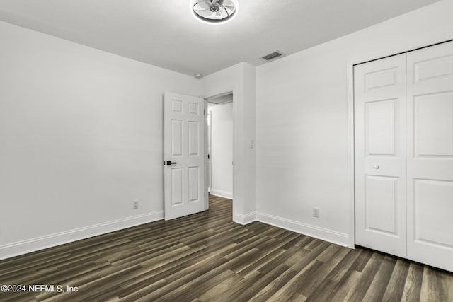 unfurnished bedroom featuring dark wood-type flooring and a closet