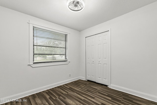 unfurnished bedroom with dark hardwood / wood-style flooring and a closet