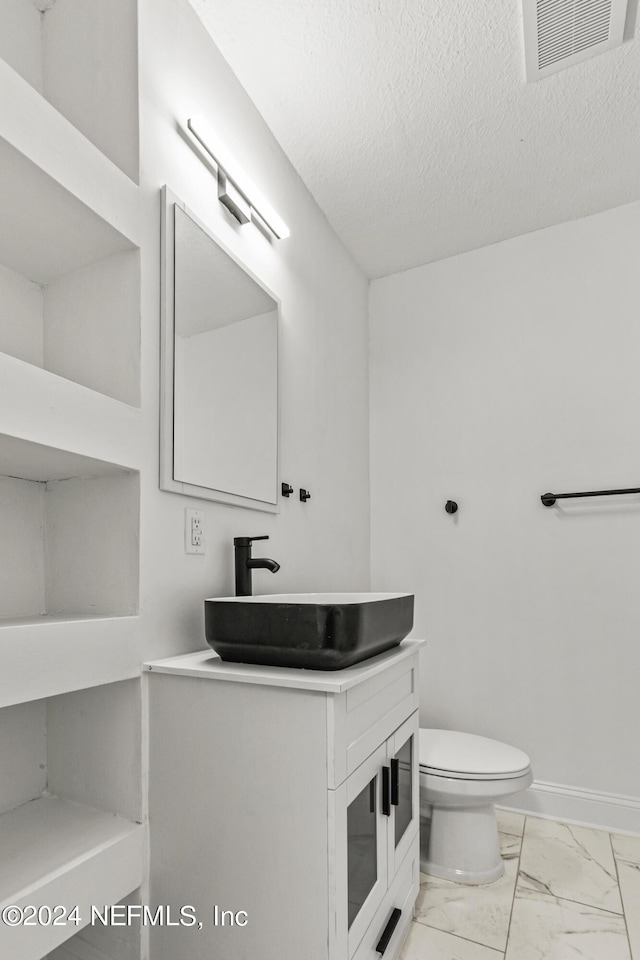 bathroom featuring vanity, a textured ceiling, and toilet