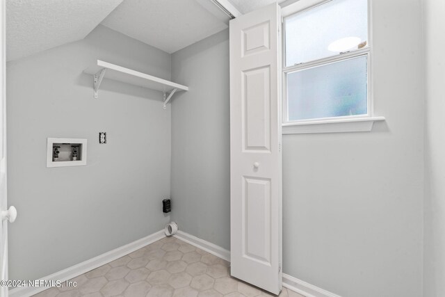 laundry room featuring a textured ceiling, light tile patterned floors, and washer hookup