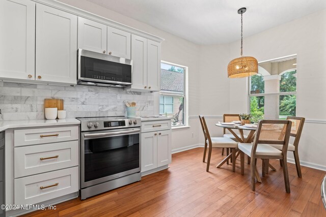 kitchen featuring white cabinets, backsplash, light hardwood / wood-style floors, and appliances with stainless steel finishes