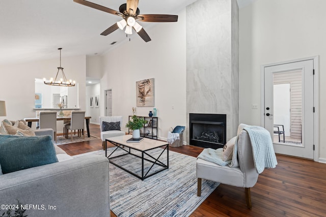 living room featuring a large fireplace, dark hardwood / wood-style flooring, ceiling fan with notable chandelier, and high vaulted ceiling