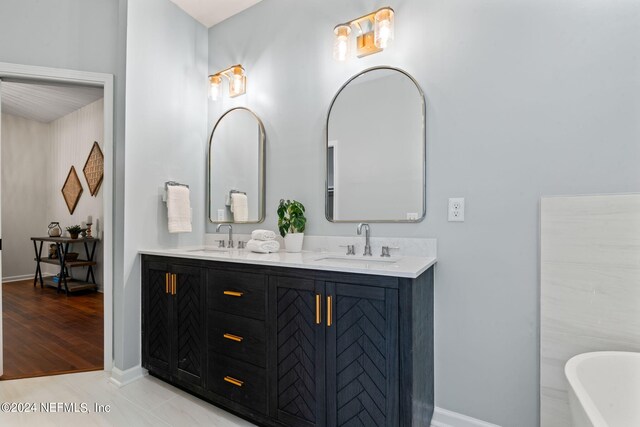 bathroom featuring dual vanity, a bathing tub, and wood-type flooring