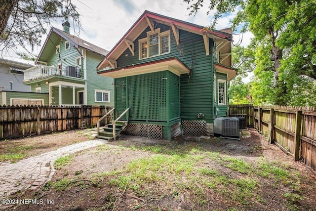 rear view of house with entry steps, a fenced backyard, and cooling unit