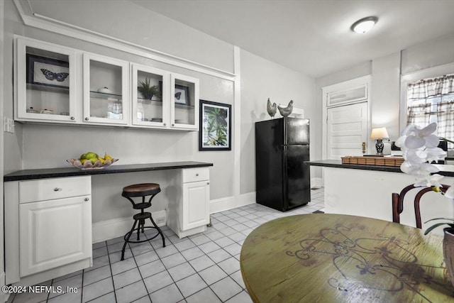 kitchen with glass insert cabinets, dark countertops, white cabinetry, and freestanding refrigerator