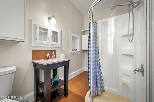 full bathroom featuring toilet, a shower with shower curtain, a sink, wood finished floors, and baseboards