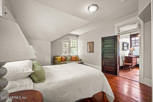 bedroom with baseboards, vaulted ceiling, and hardwood / wood-style floors