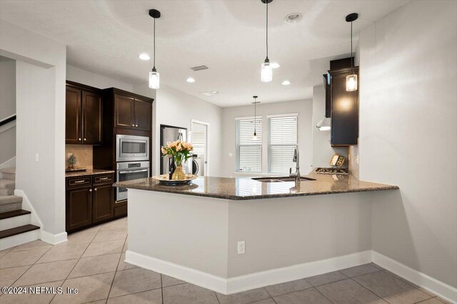 kitchen with dark brown cabinets, light tile patterned floors, sink, appliances with stainless steel finishes, and kitchen peninsula