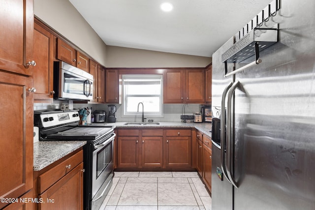 kitchen featuring light stone countertops, appliances with stainless steel finishes, tasteful backsplash, sink, and lofted ceiling