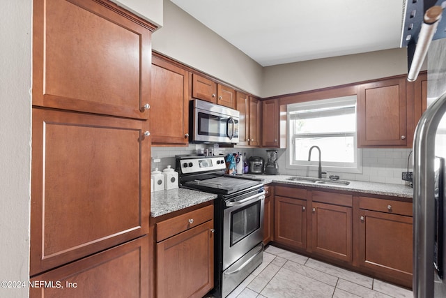 kitchen with sink, light stone counters, decorative backsplash, and appliances with stainless steel finishes