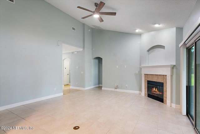 unfurnished living room with a high ceiling, ceiling fan, a textured ceiling, and a fireplace