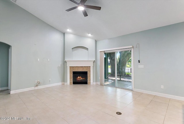 unfurnished living room featuring ceiling fan, a tiled fireplace, and light tile patterned floors