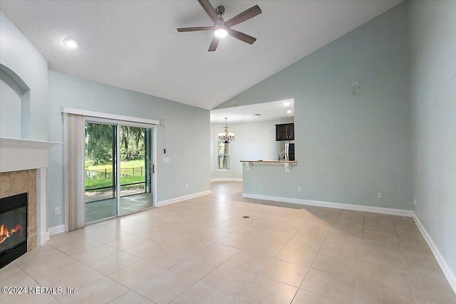 unfurnished living room featuring ceiling fan with notable chandelier, a tiled fireplace, high vaulted ceiling, and light tile patterned floors