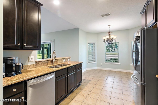 kitchen featuring sink, light stone counters, light tile patterned floors, appliances with stainless steel finishes, and a healthy amount of sunlight