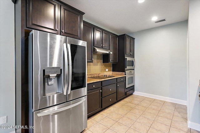 kitchen with light stone counters, dark brown cabinetry, stainless steel appliances, and light tile patterned flooring