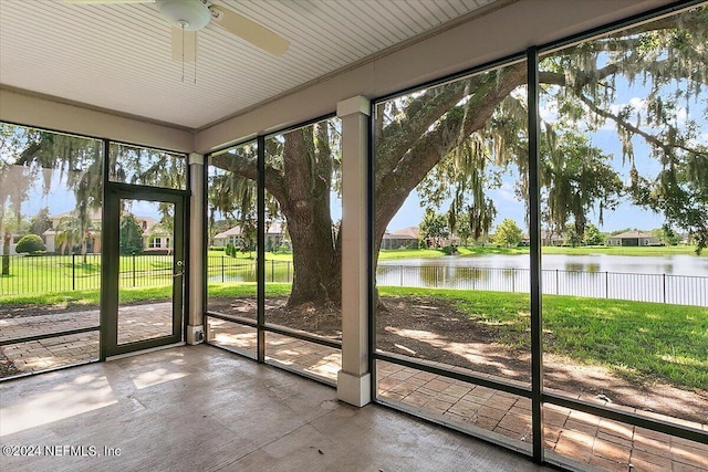 unfurnished sunroom with ceiling fan, a healthy amount of sunlight, and a water view