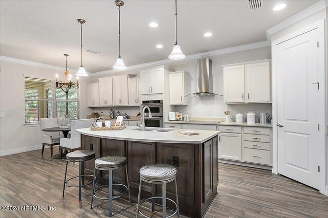 kitchen featuring decorative light fixtures, wall chimney exhaust hood, sink, double oven, and dark wood-type flooring