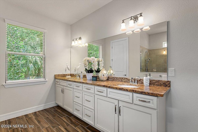 bathroom with tiled shower and vanity