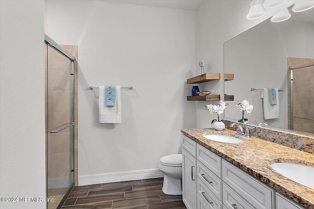 bathroom featuring toilet, vanity, and a shower with door