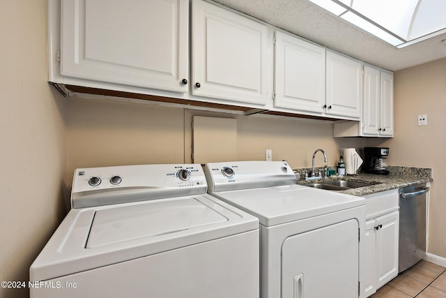 laundry area with sink, washing machine and clothes dryer, a skylight, and light tile patterned flooring