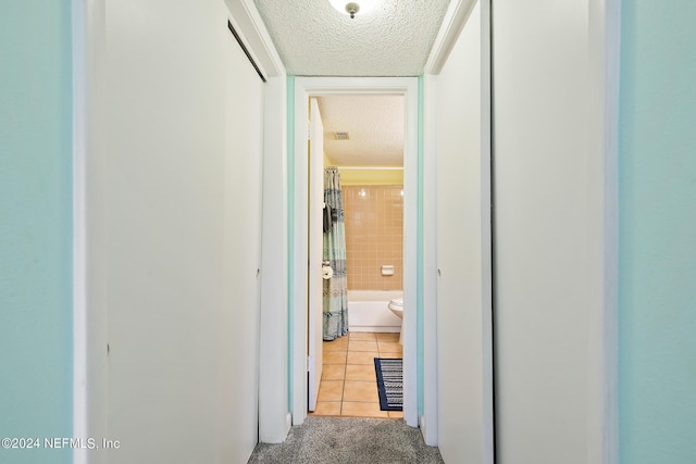 corridor with a textured ceiling and light tile patterned floors