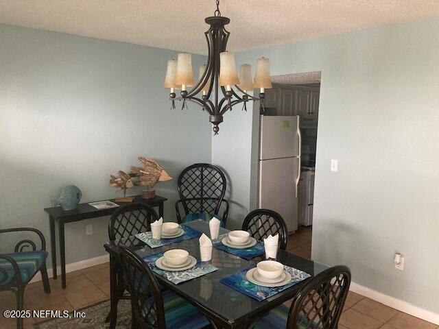 dining room with light tile patterned floors, baseboards, a textured ceiling, and an inviting chandelier