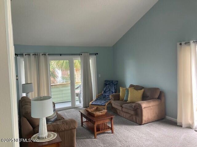 living area with baseboards, carpet, and vaulted ceiling