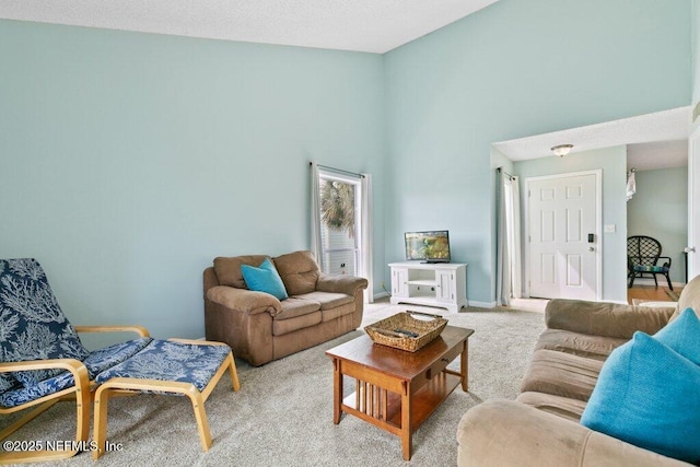 carpeted living area featuring a high ceiling and baseboards