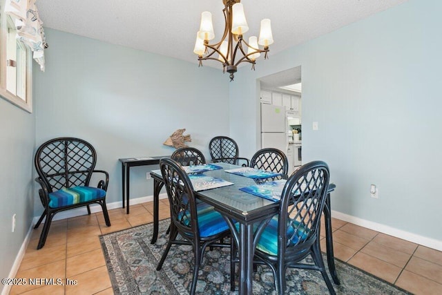 dining space with baseboards, a textured ceiling, a notable chandelier, and light tile patterned floors