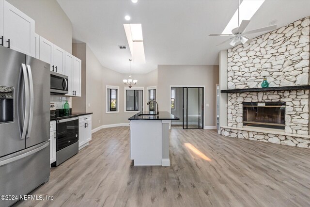 kitchen featuring white cabinetry, ceiling fan with notable chandelier, a center island with sink, appliances with stainless steel finishes, and light hardwood / wood-style flooring