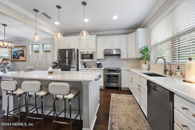 kitchen with a center island, stainless steel appliances, sink, and decorative light fixtures