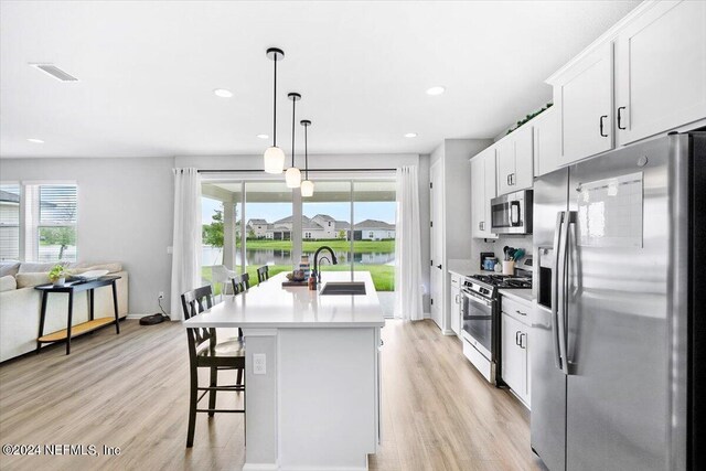 kitchen featuring appliances with stainless steel finishes, plenty of natural light, a center island with sink, and light wood-type flooring