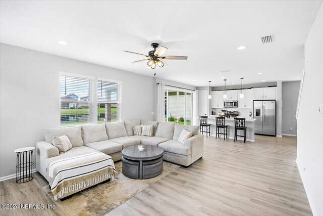 living room with light wood-type flooring and ceiling fan