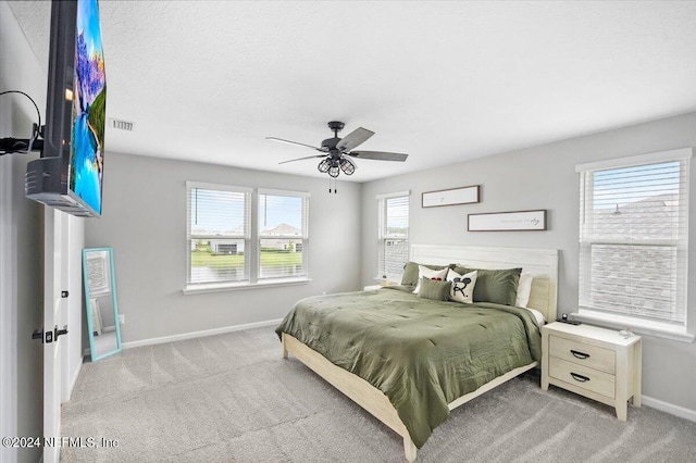 carpeted bedroom featuring multiple windows and ceiling fan