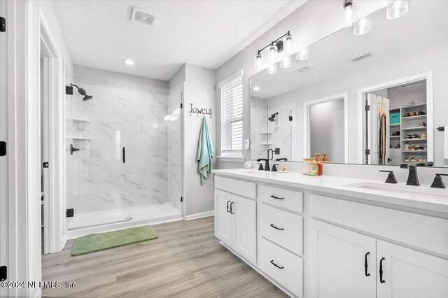 bathroom featuring hardwood / wood-style flooring, dual vanity, and a shower with door