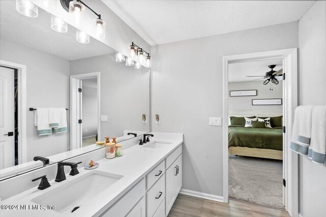 bathroom featuring double vanity, ceiling fan, a textured ceiling, and hardwood / wood-style flooring