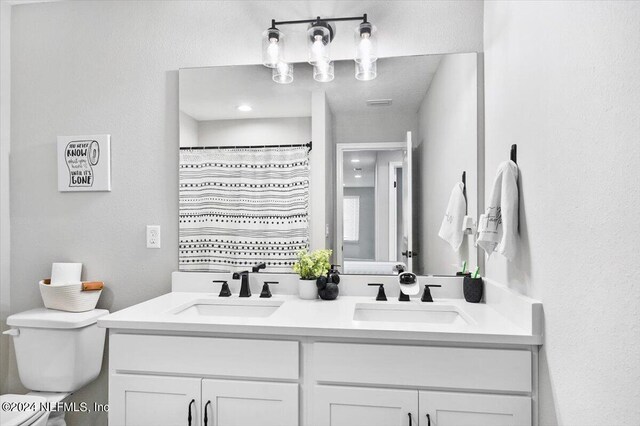 bathroom with dual bowl vanity and toilet