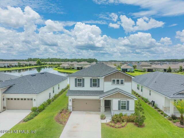 view of front facade featuring a garage, a water view, and a front lawn