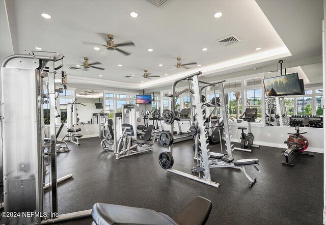 gym featuring ceiling fan and a tray ceiling