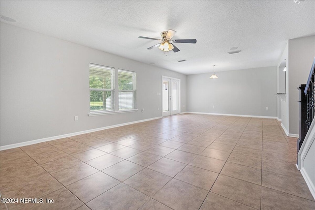 unfurnished living room with ceiling fan, light tile patterned floors, french doors, and a textured ceiling