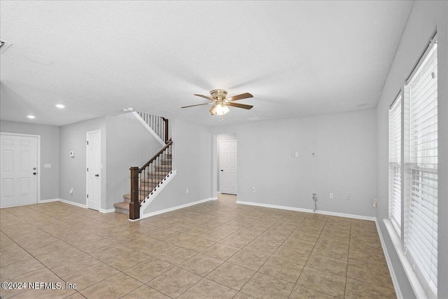 empty room featuring ceiling fan, a textured ceiling, and light tile patterned floors