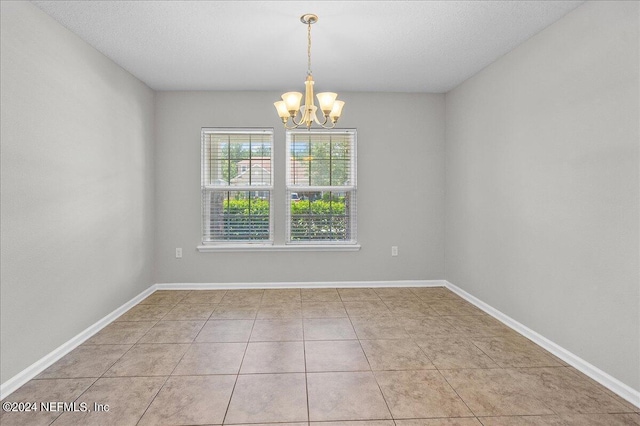 spare room featuring light tile patterned floors and a chandelier