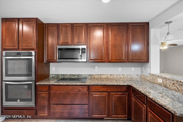 kitchen with ceiling fan, hanging light fixtures, stainless steel appliances, a textured ceiling, and light stone counters