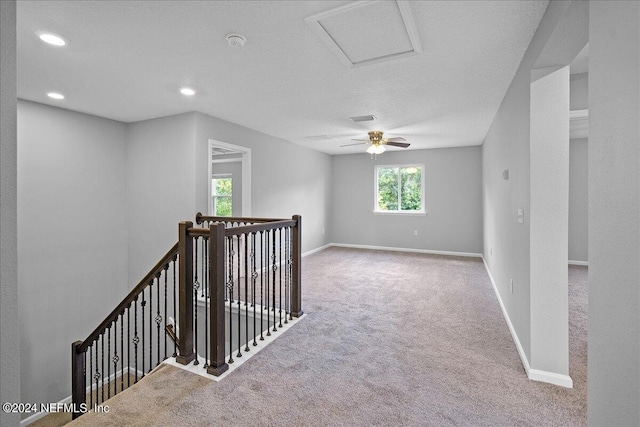 hall featuring light carpet, a textured ceiling, and plenty of natural light